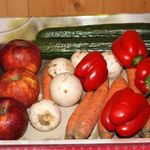 Einige frische Gemüsesorten, die in einem Karton liegen: Äpfel, Möhren, Paprika, Salatgrken und Pilze