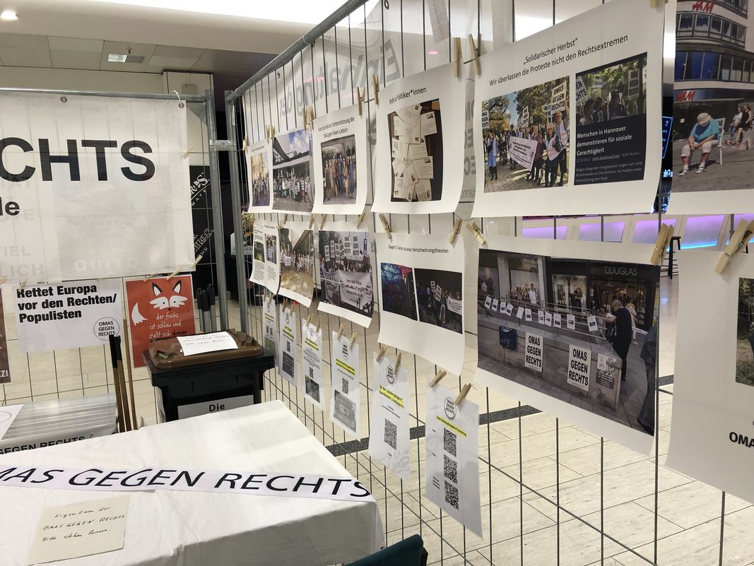 Foto des Infostandes der „Omas gegen Rechts“ im aufhof. An einem Gitter hängen Informationen und Fotos von ihren Aktionen.  